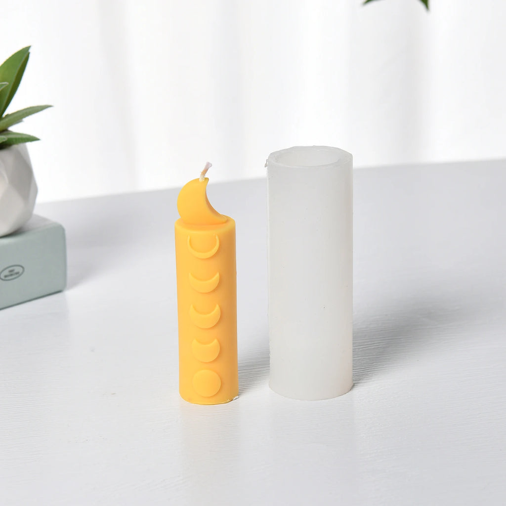 Yellow crescent-top moon-phase pillar example candle beside a white cylindrical silicone mold