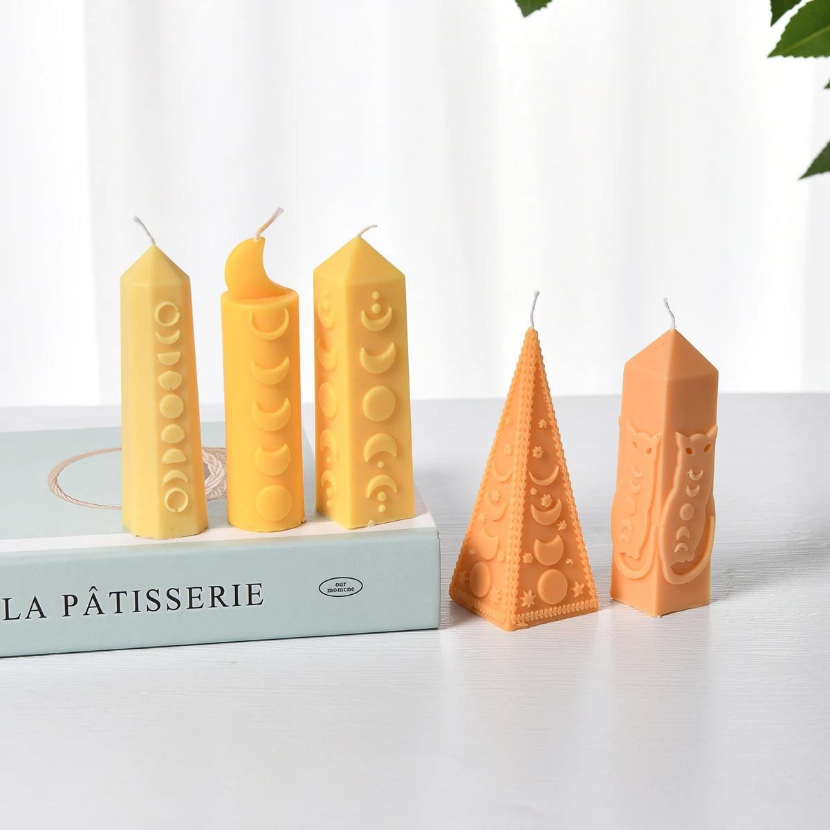 Five yellow and orange moon-phase example candles in pointed pillar, crescent-top and triangular shapes