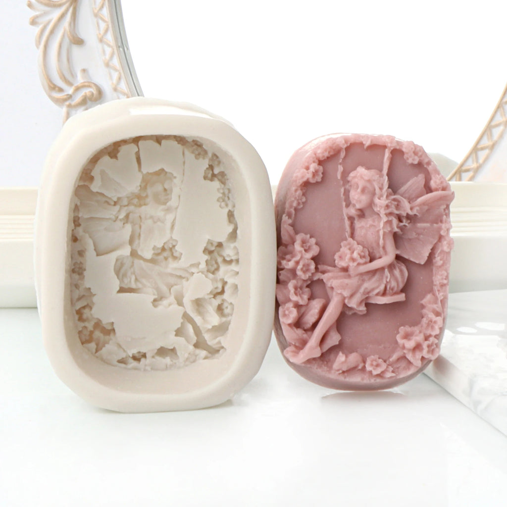 Pink fairy-on-a-swing oval relief casting example beside its white silicone mold