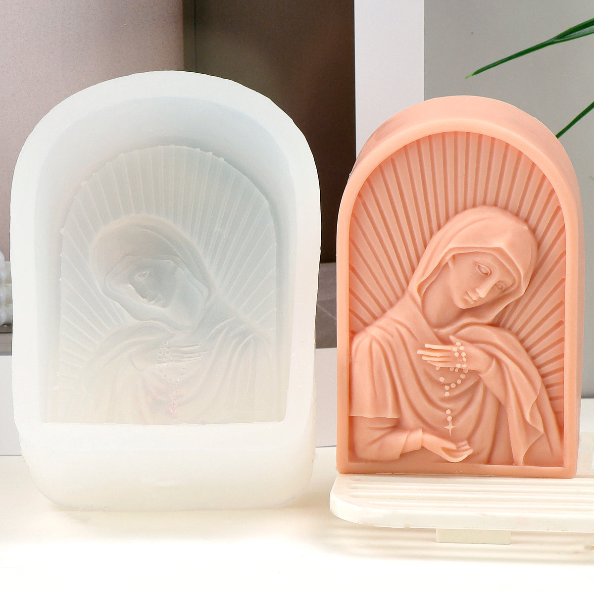Peach bowed Virgin Mary relief casting beside its white arched silicone mold