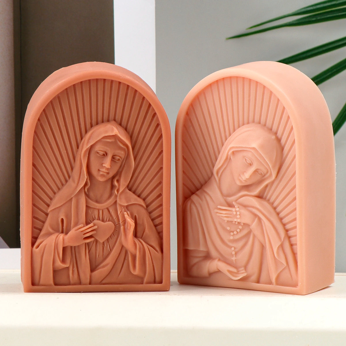 Two peach arched Virgin Mary relief casting examples with radiating backgrounds