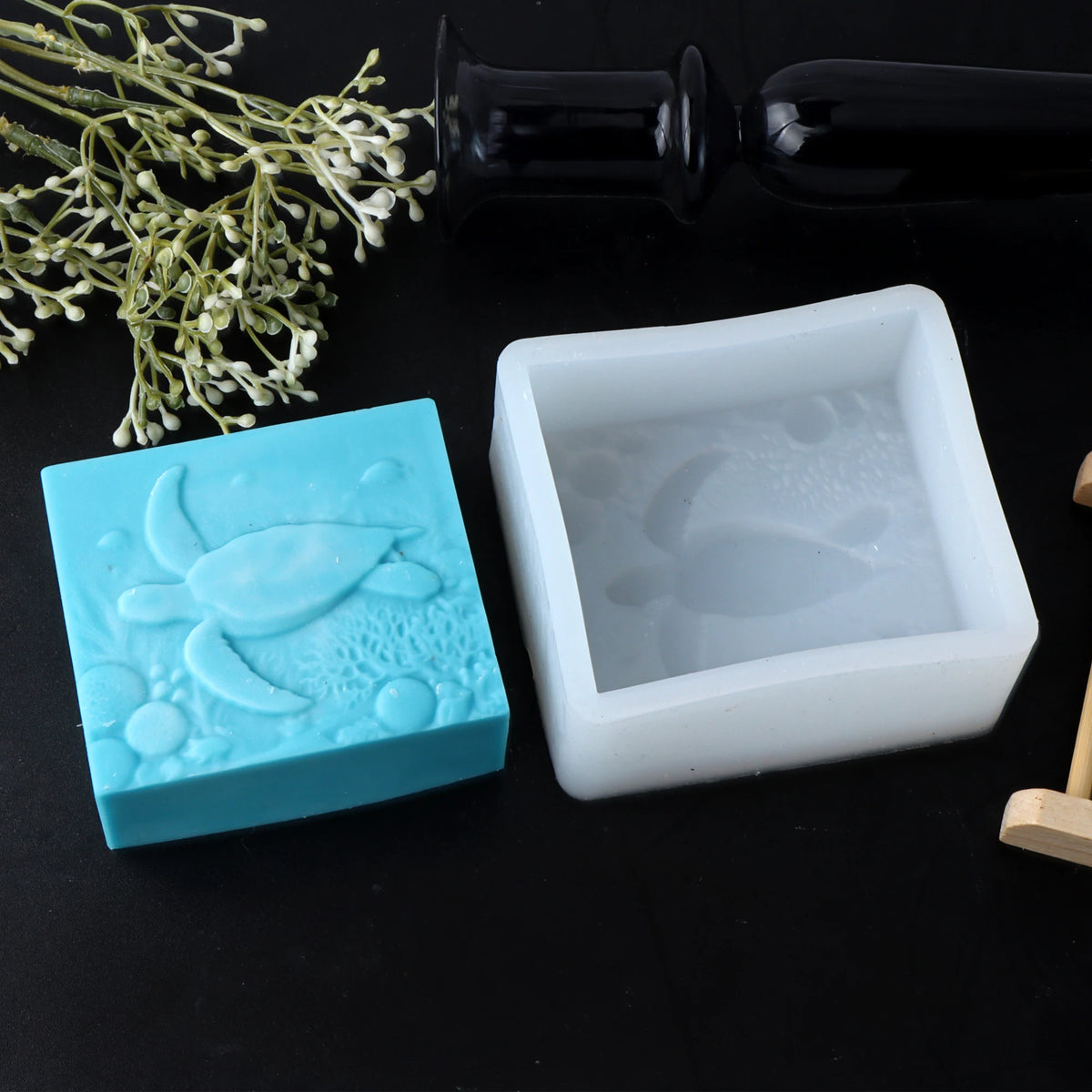 Turquoise sea-turtle soap casting beside its white square silicone mold