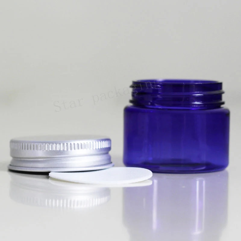 Blue empty round jar beside a silver-tone screw lid and white liner