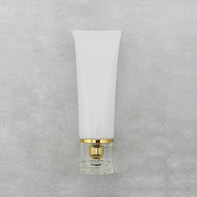 White squeeze tube with gold-tone dispensing closure and clear cover, style 7