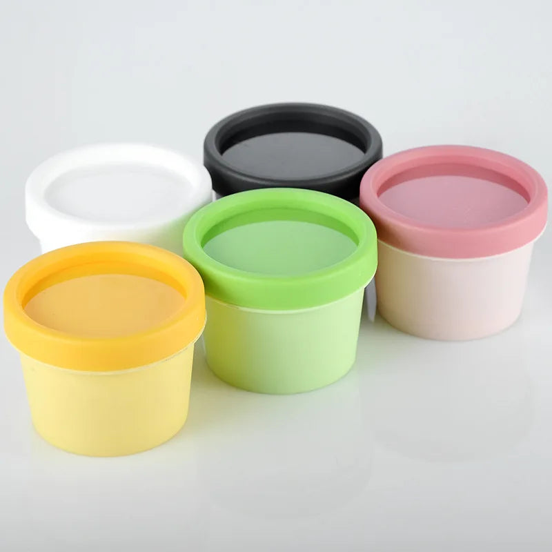 Empty round plastic jars with yellow, green, pink, white and black lids