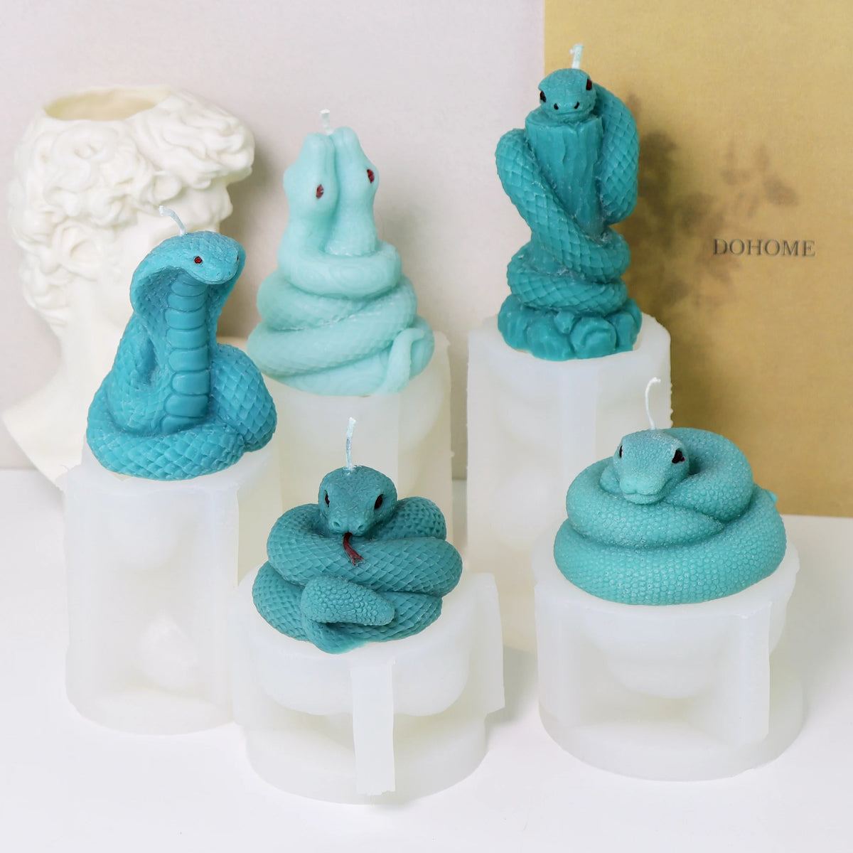 Five turquoise snake example candles displayed on their corresponding white silicone molds