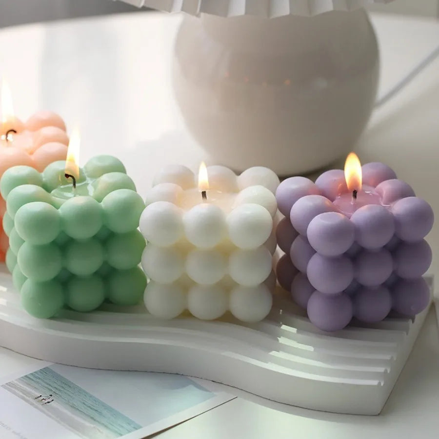 Lit green, white and lavender bubble cube candles displayed on a white tray