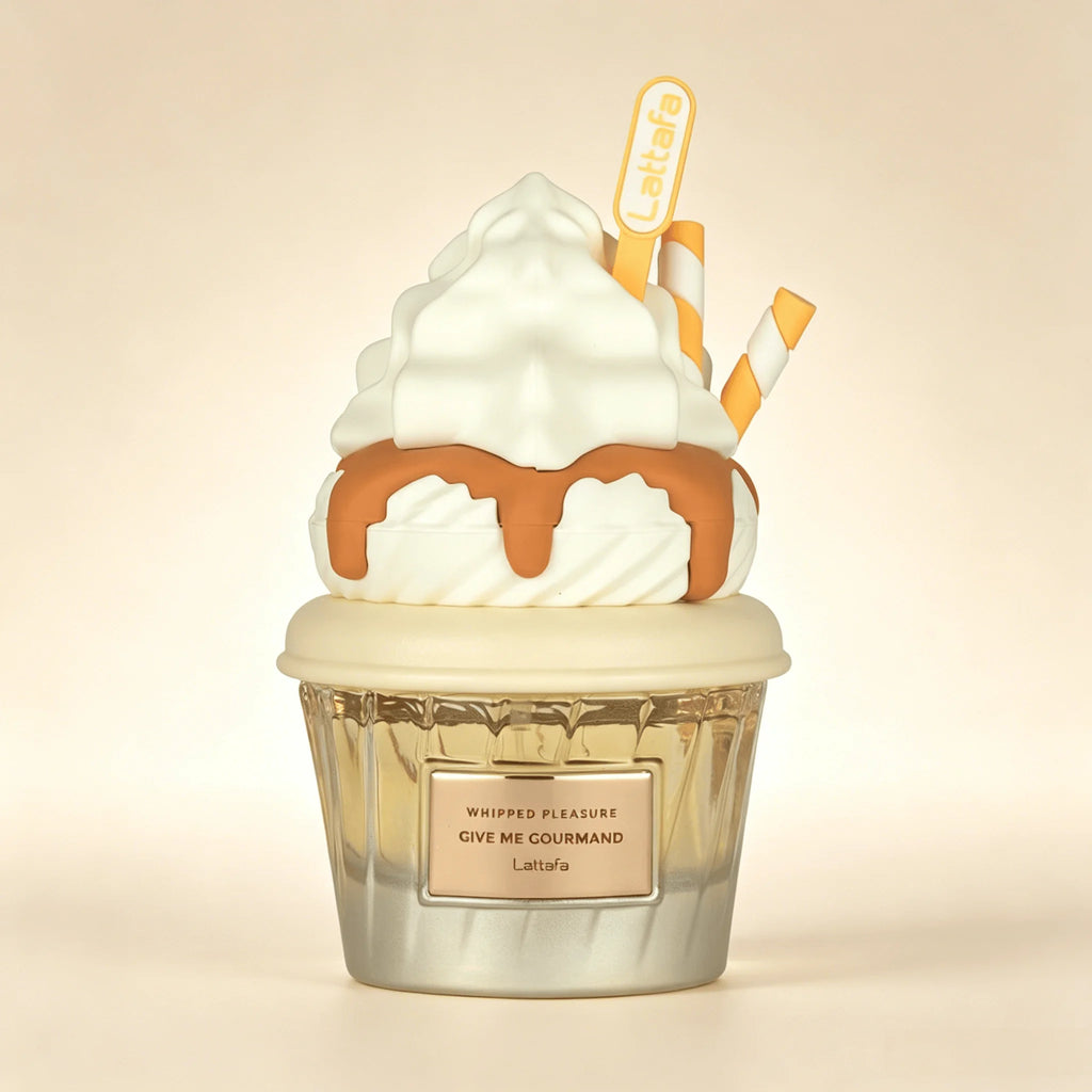 A Lattafa Perfume whipped cream and caramel sauce cupcake-shaped fragrance diffuser or candle. The design features white whipped cream, caramel brown drizzle, a clear ribbed glass cup, and two yellow-and-white striped straws, all set against a warm beige background.