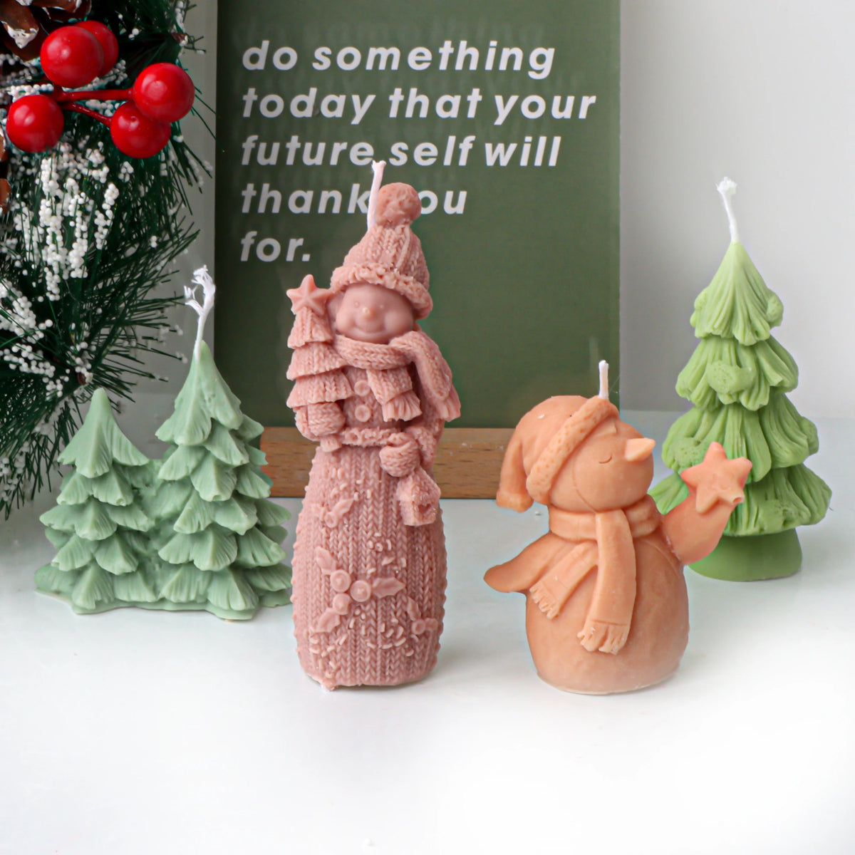 Pastel Christmas tree cluster, single tree and two snowman example candles beside holiday greenery