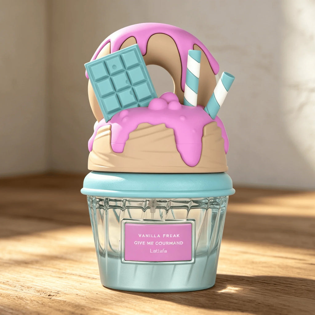 A novelty cupcake-shaped Lattafa perfume bottle with a light blue wrapper, pink frosting, a tan vanilla cream layer, a blue chocolate bar, and striped straws, sitting on a wooden table.