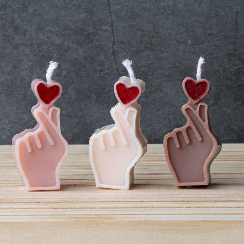 Three finger-heart example candles with red hearts and pale pink, ivory and brown hands