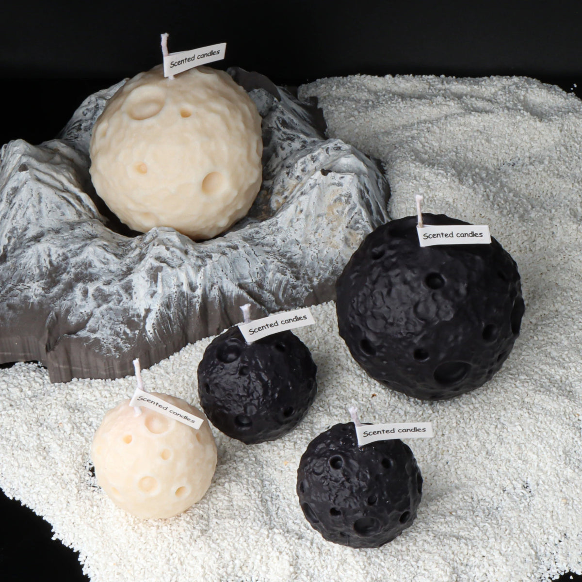 Black and ivory moon candles in several pictured sizes arranged around a lunar landscape display