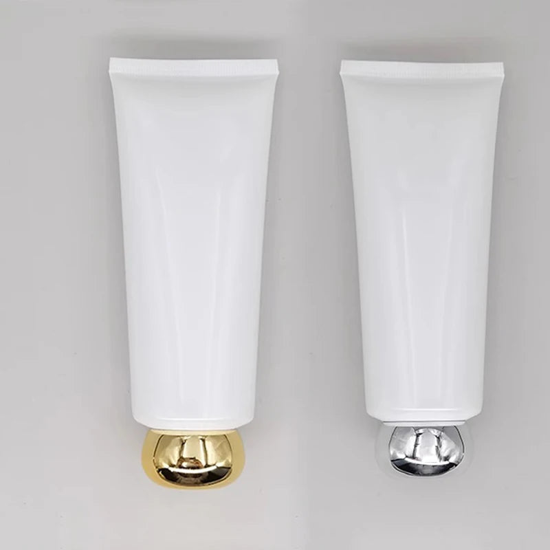 White squeeze tubes with rounded gold-tone and silver-tone caps