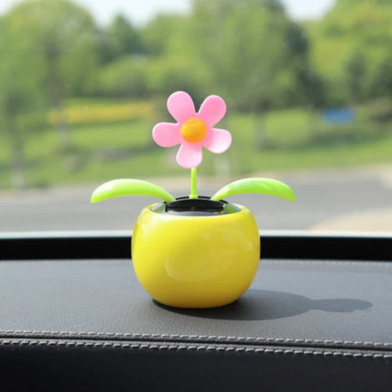 Colorful flower-shaped toy on a car dashboard with a blurred green outdoor background