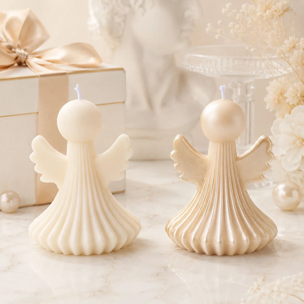 Two ivory pleated angel example candles with plain and gold-colored wing details