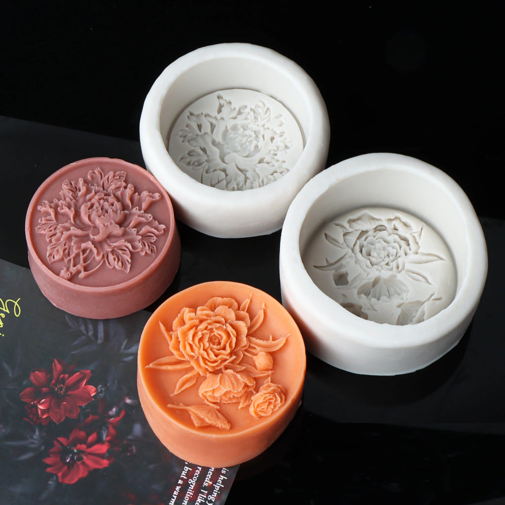 Mauve and orange round peony relief casting examples beside white silicone molds