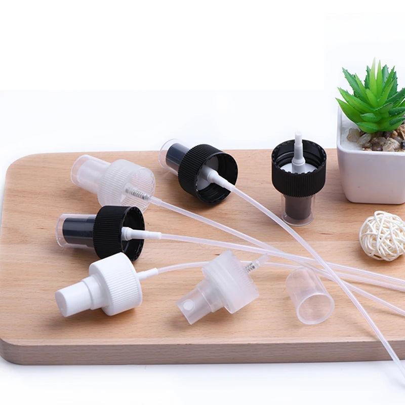 Black, white and clear spray mechanisms with dip tubes on a wooden tray