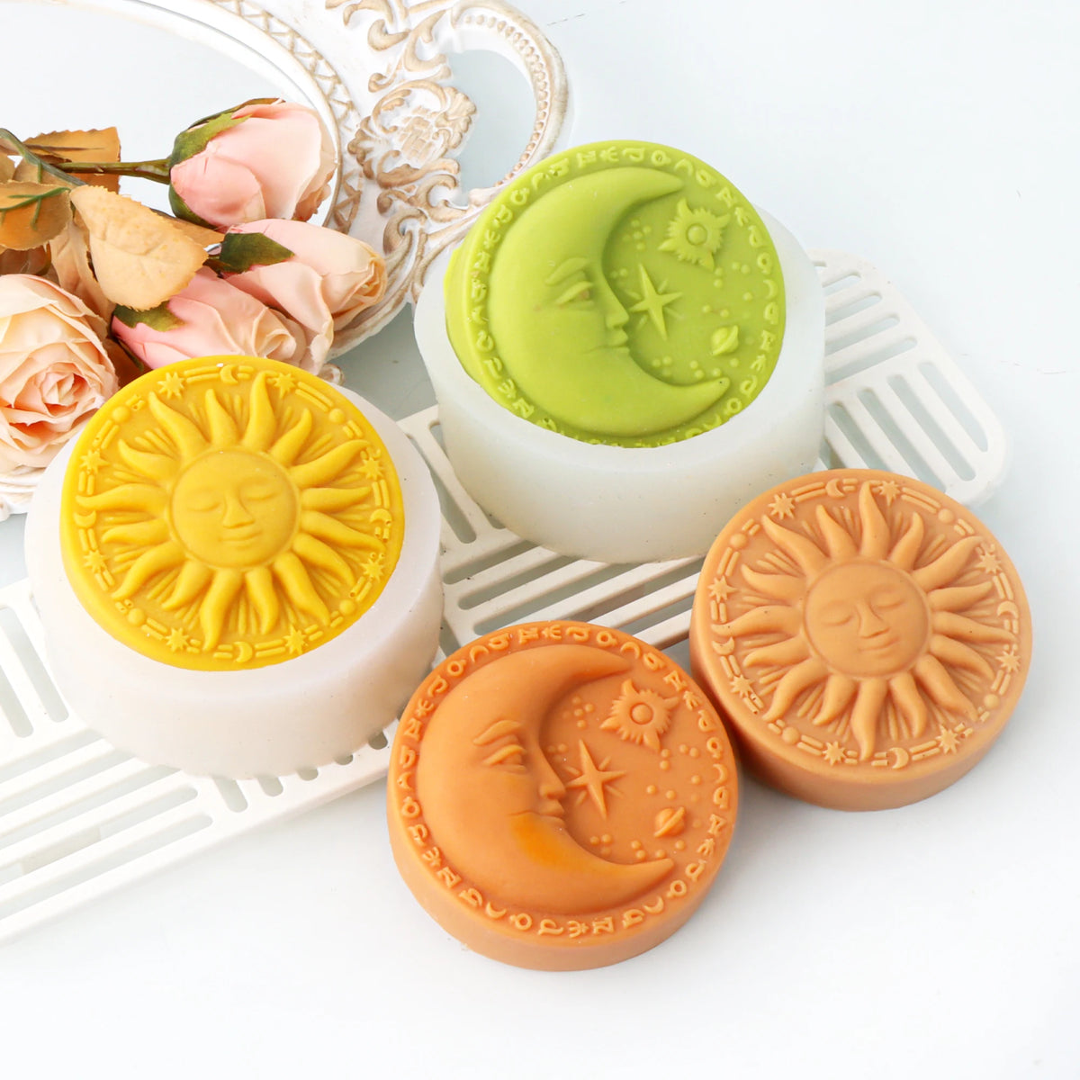 Four sun-face and crescent-moon face soap casting examples displayed with white silicone molds