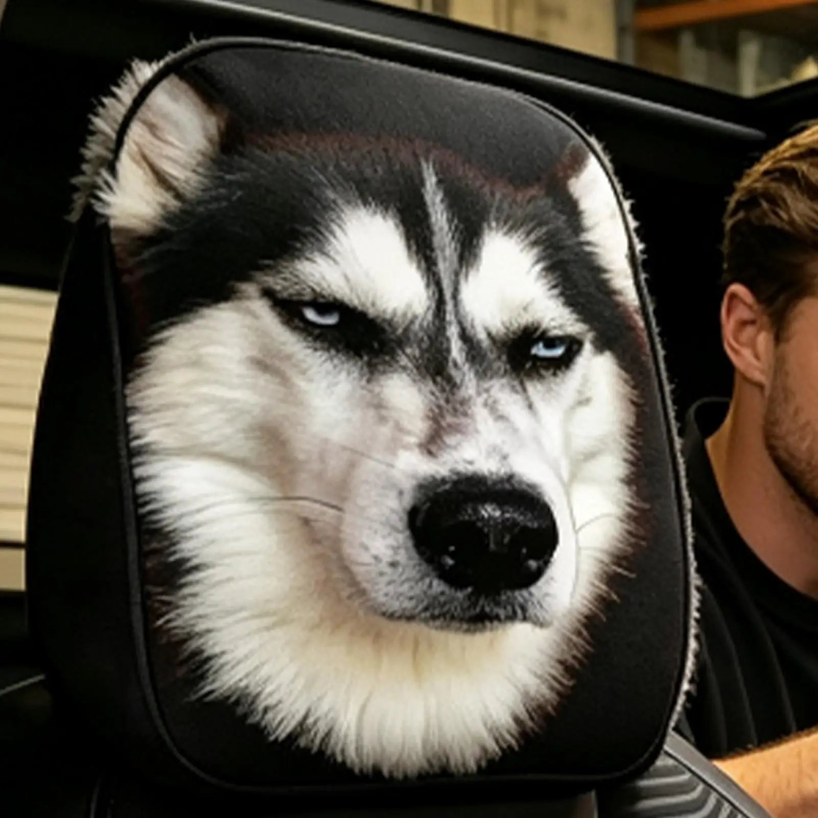 A car headrest cover featuring a printed husky dog face, shown installed on a car seat with part of a person visible in the background.