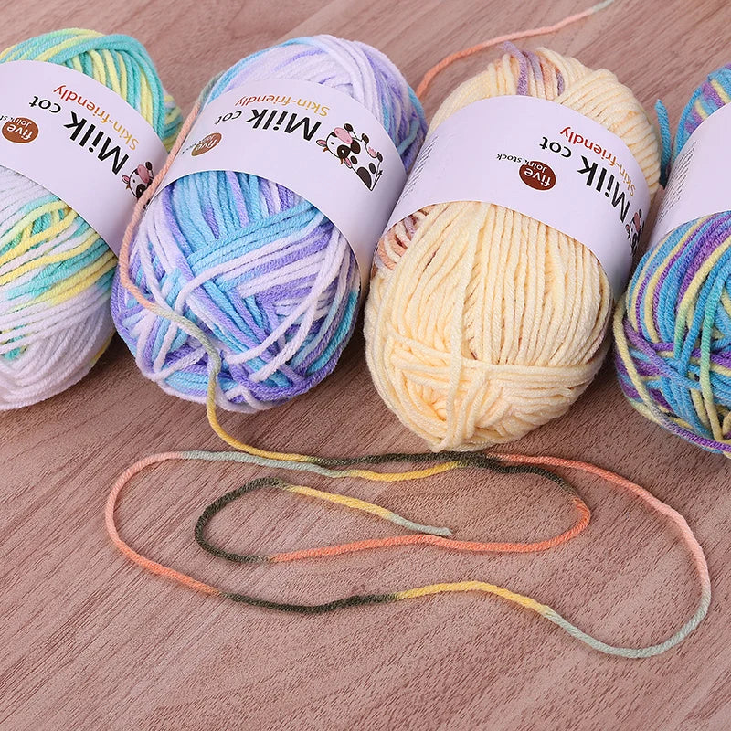 Pastel variegated yarn skeins with loose multicolored strands on a wooden surface.