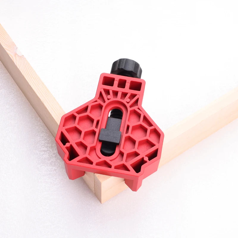 A red plastic framing square with a black adjustment knob, shown clamped onto two wooden boards against a white background.