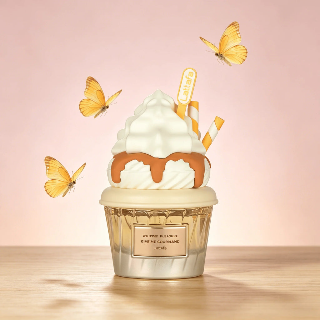A Lattafa Perfume cupcake-shaped perfume bottle on a wooden surface against a soft pink background, decorated with white whipped cream, caramel drizzle, striped straws, and yellow butterflies. The bottle label reads 'Whipped Vanilla Give Me Courrègo'.