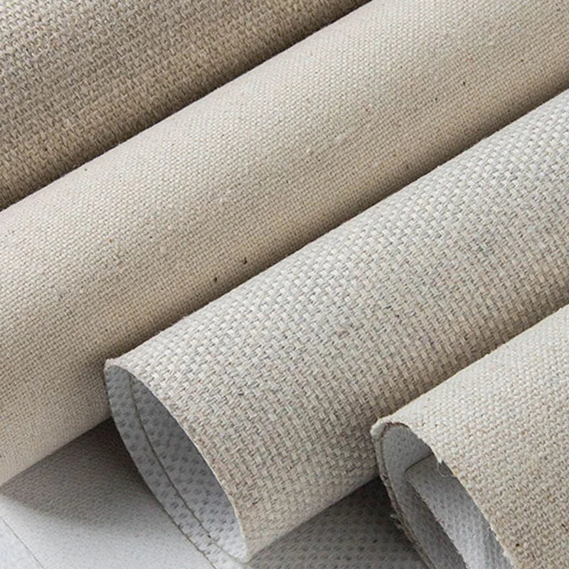 Close-up of several rolled beige woven canvas samples stacked on a light surface, showing the texture and underside.