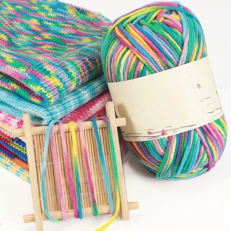 Pink, turquoise, green and yellow variegated yarn beside knitted swatches and strands on a wooden frame.
