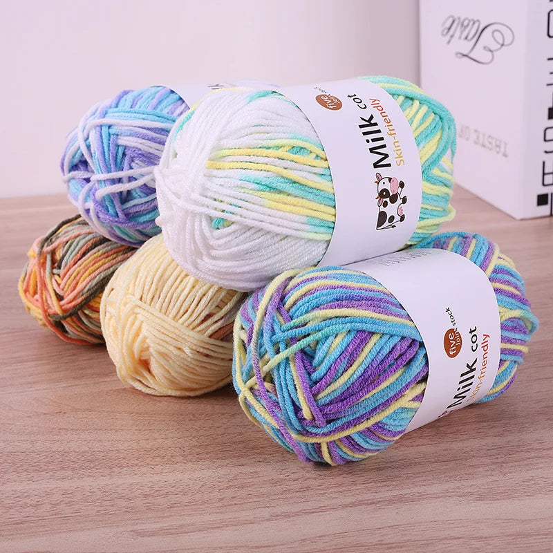 Pastel variegated yarn skeins in turquoise, purple, yellow, white and peach shades on a wooden surface.