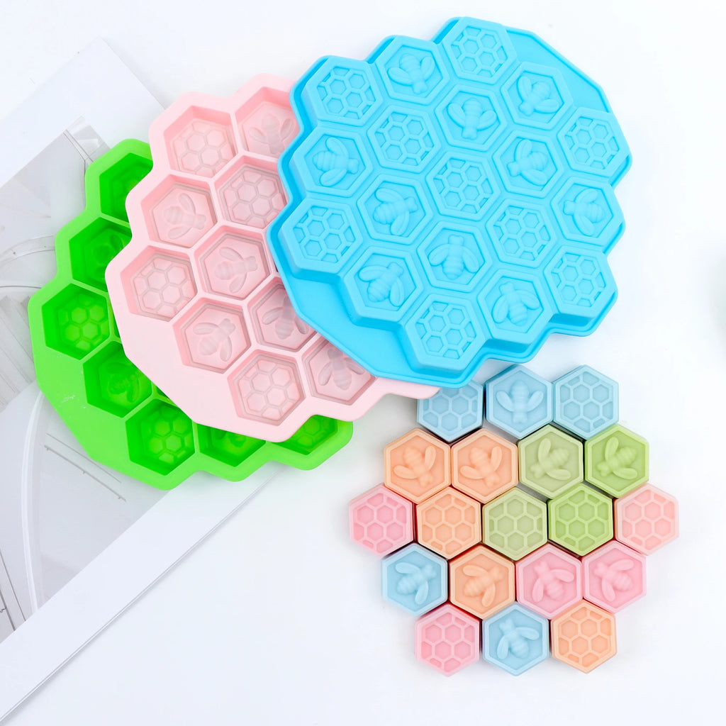 Green, pink and blue multi-cavity silicone molds beside pastel bee and honeycomb example castings