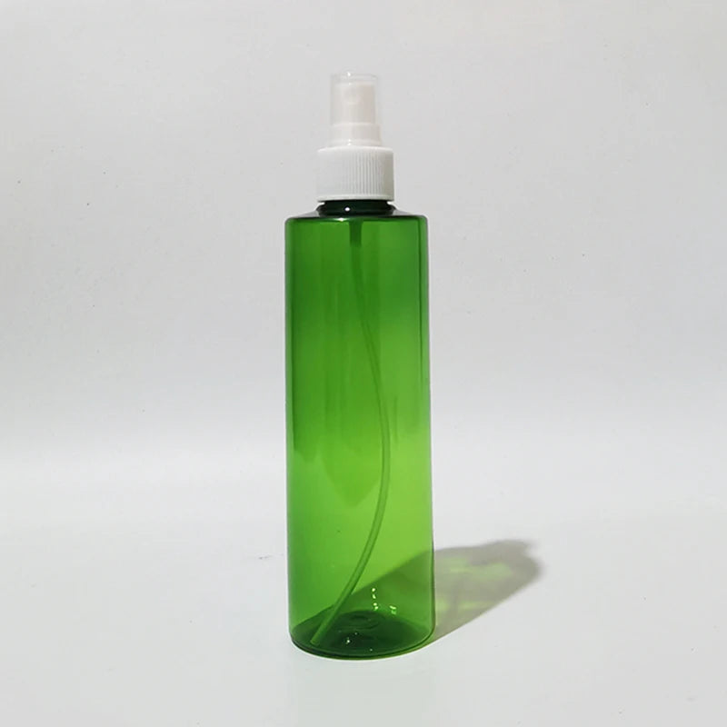Green empty round bottle with a white spray pump and clear protective cover