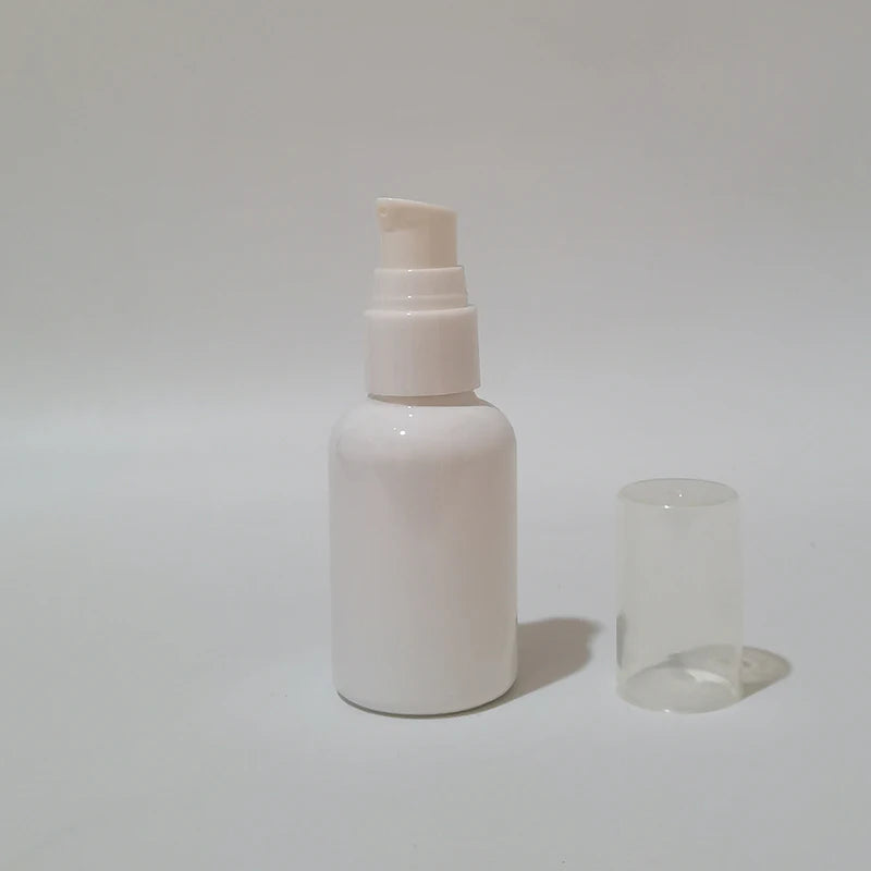 White empty round bottle with a white pump and clear protective cover beside it
