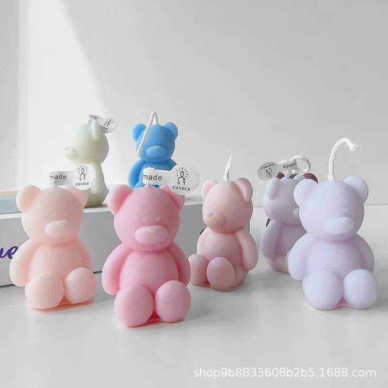 Pastel teddy bear candles in pink, lavender, green and blue arranged on a white surface