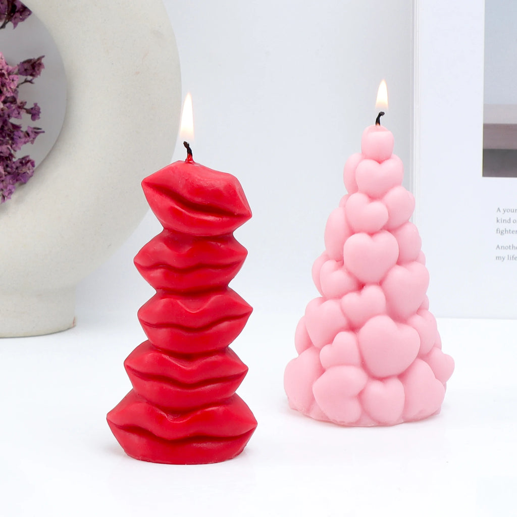 Lit red lips pillar and pink clustered-heart pillar example candles on a white surface
