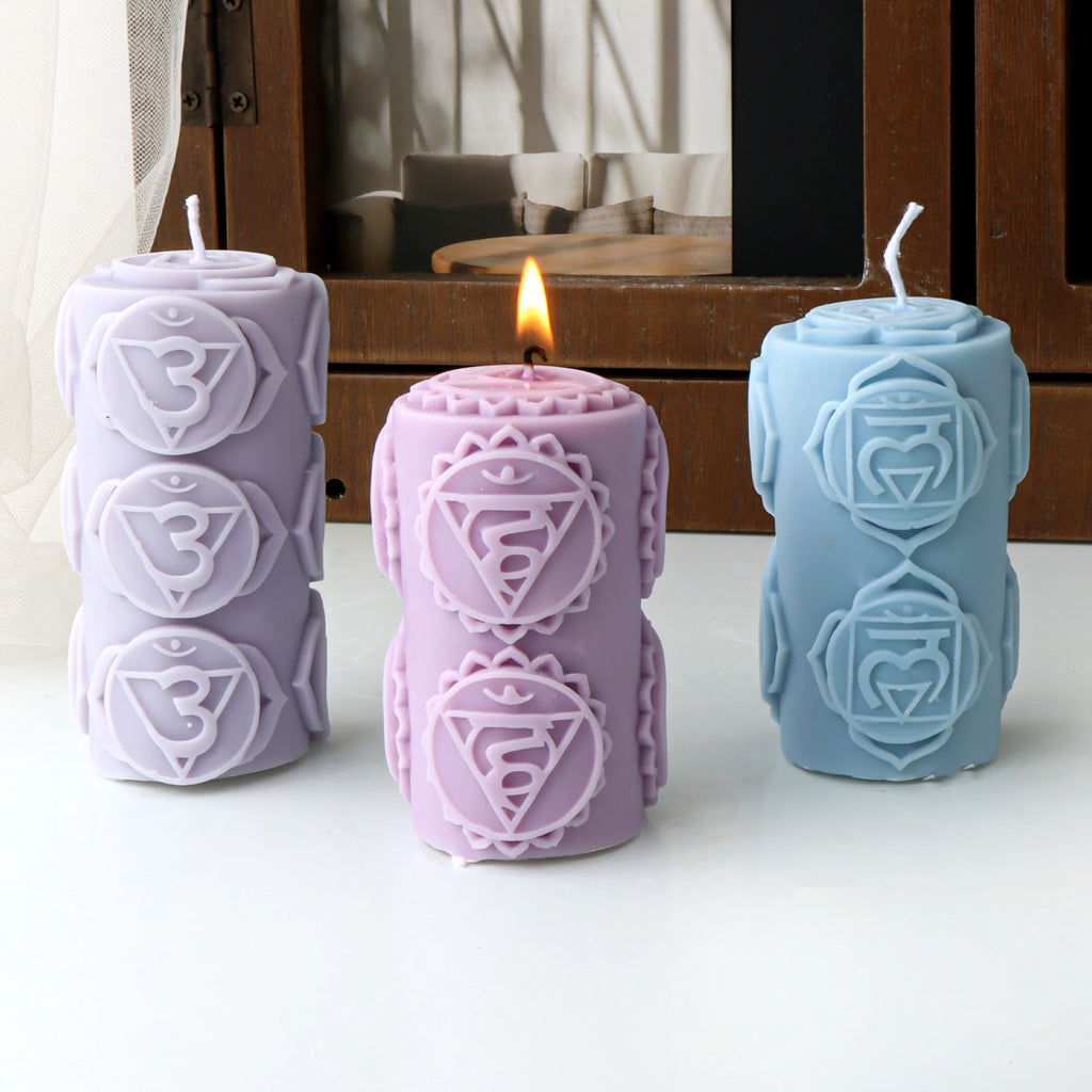 Lavender, pink and blue symbol-patterned pillar example candles with the pink candle lit