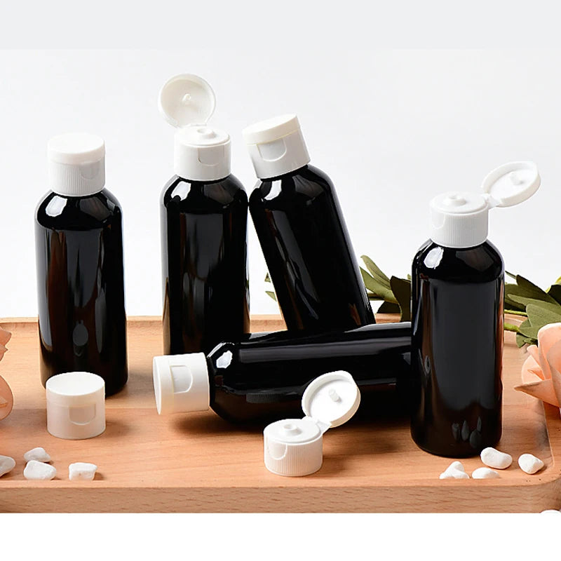Black PET bottles with white flip-top caps on a wooden tray