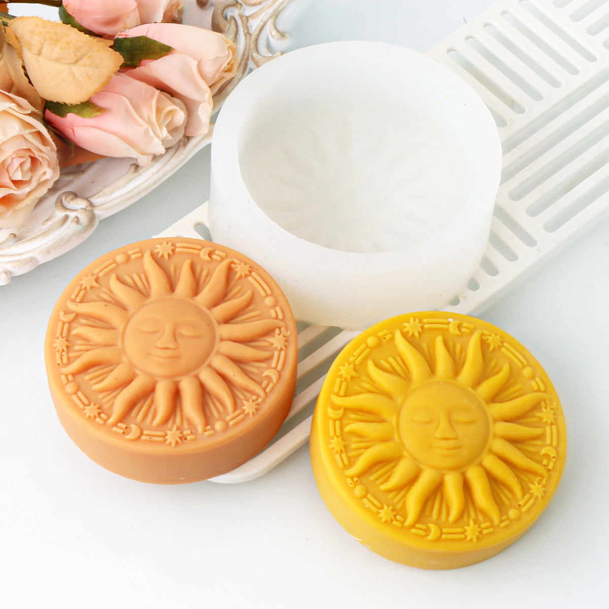 Orange and yellow sun-face soap casting examples beside a white round silicone mold