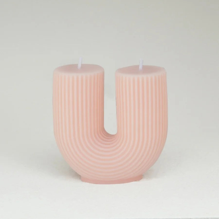 Pink U-shaped candle on a white background