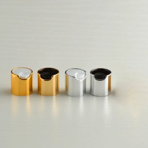 Four gold-tone and silver-tone disc-top bottle caps with white and black inserts
