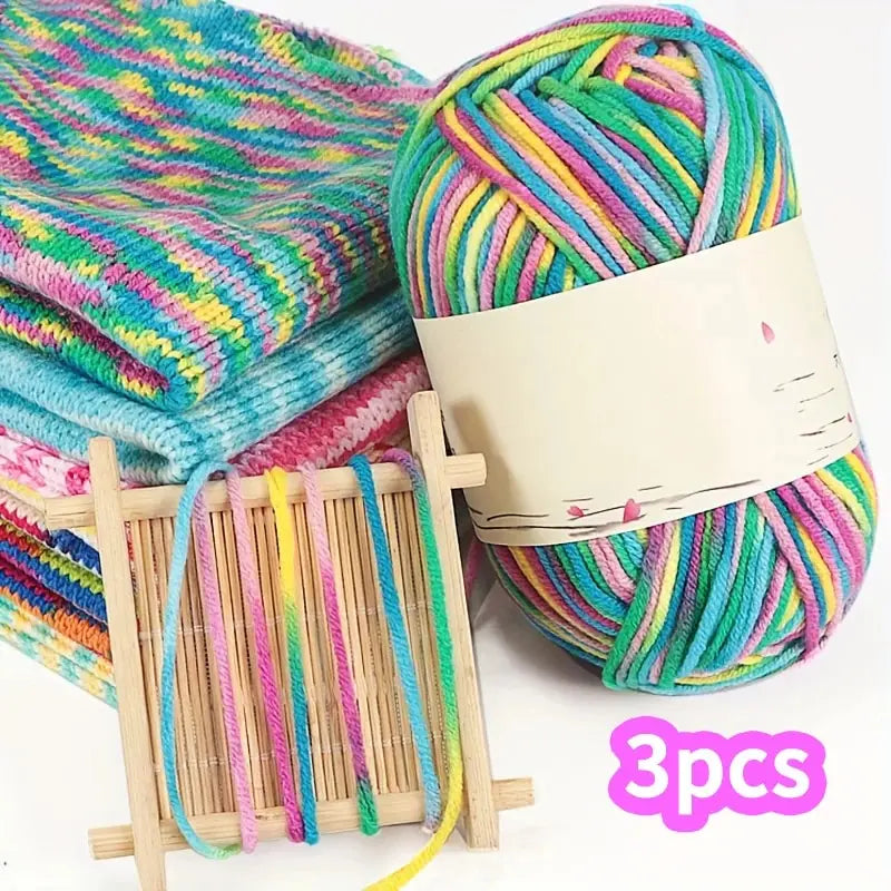 Multicolored yarn beside knitted swatches and a wooden frame, with a three-piece pack label.