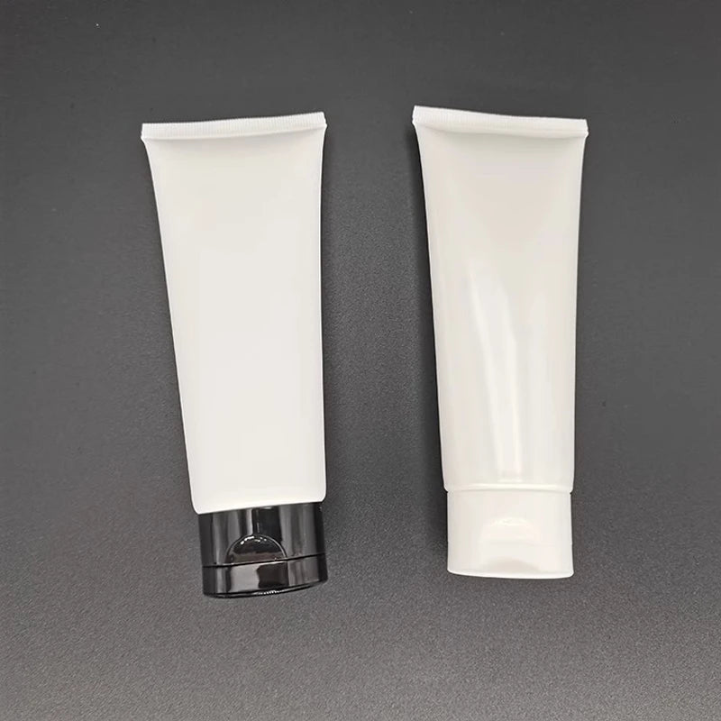 White squeeze tubes with black and white flip-style caps on a dark background