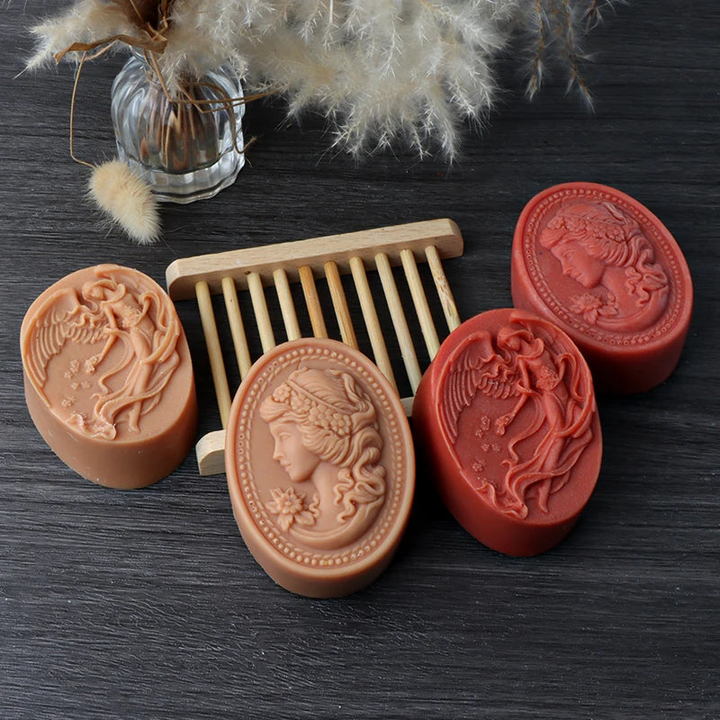 Four oval soap casting examples in tan and red with floral woman-profile and winged figure relief designs