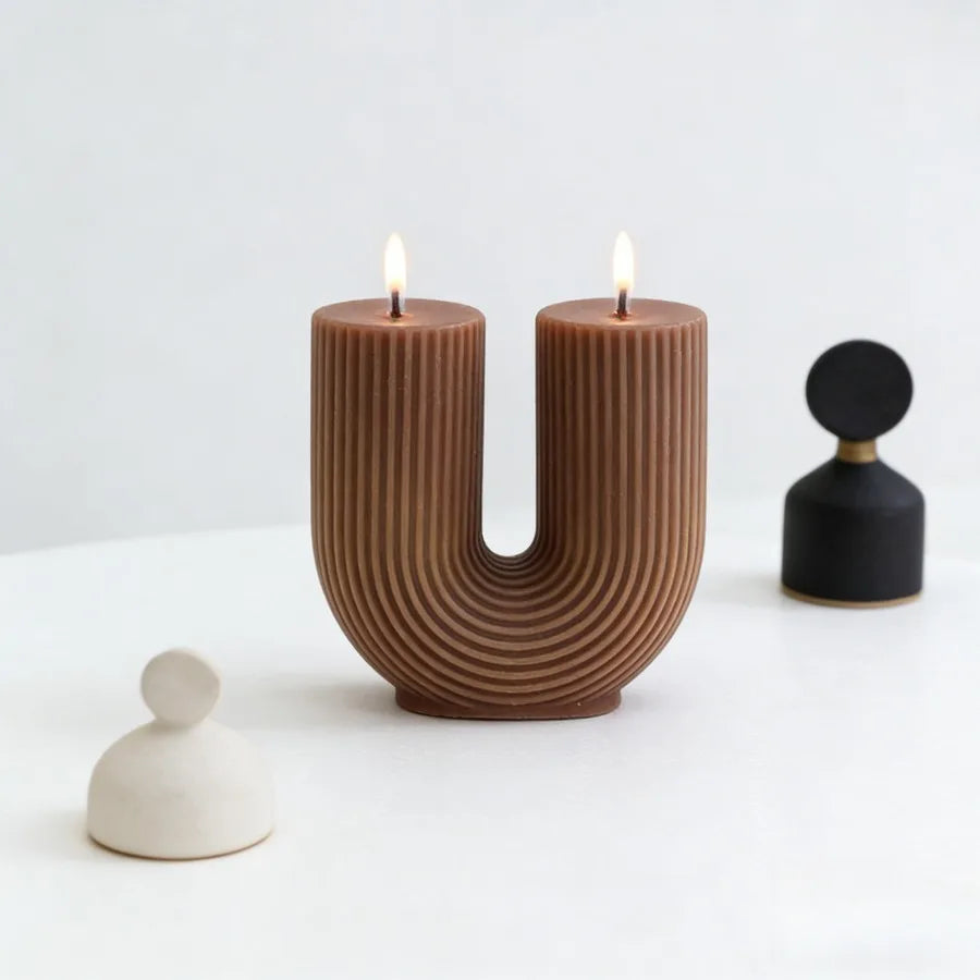 Brown U-shaped candle holder with two lit candles on a white background