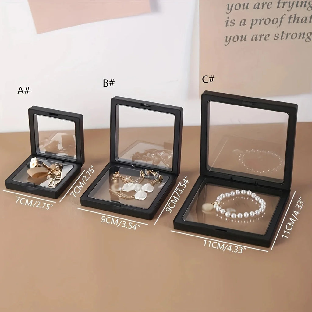 Three black jewelry display cases with jewelry items and measurements on a beige surface.