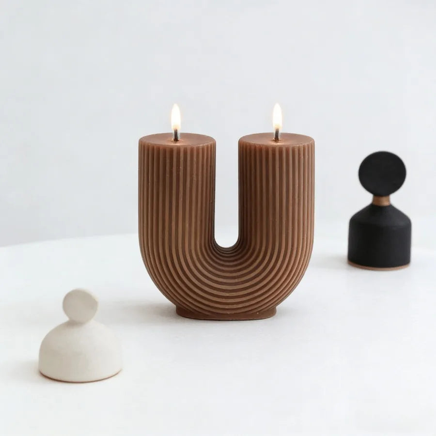 Brown U-shaped candle holder with two lit candles on a white background