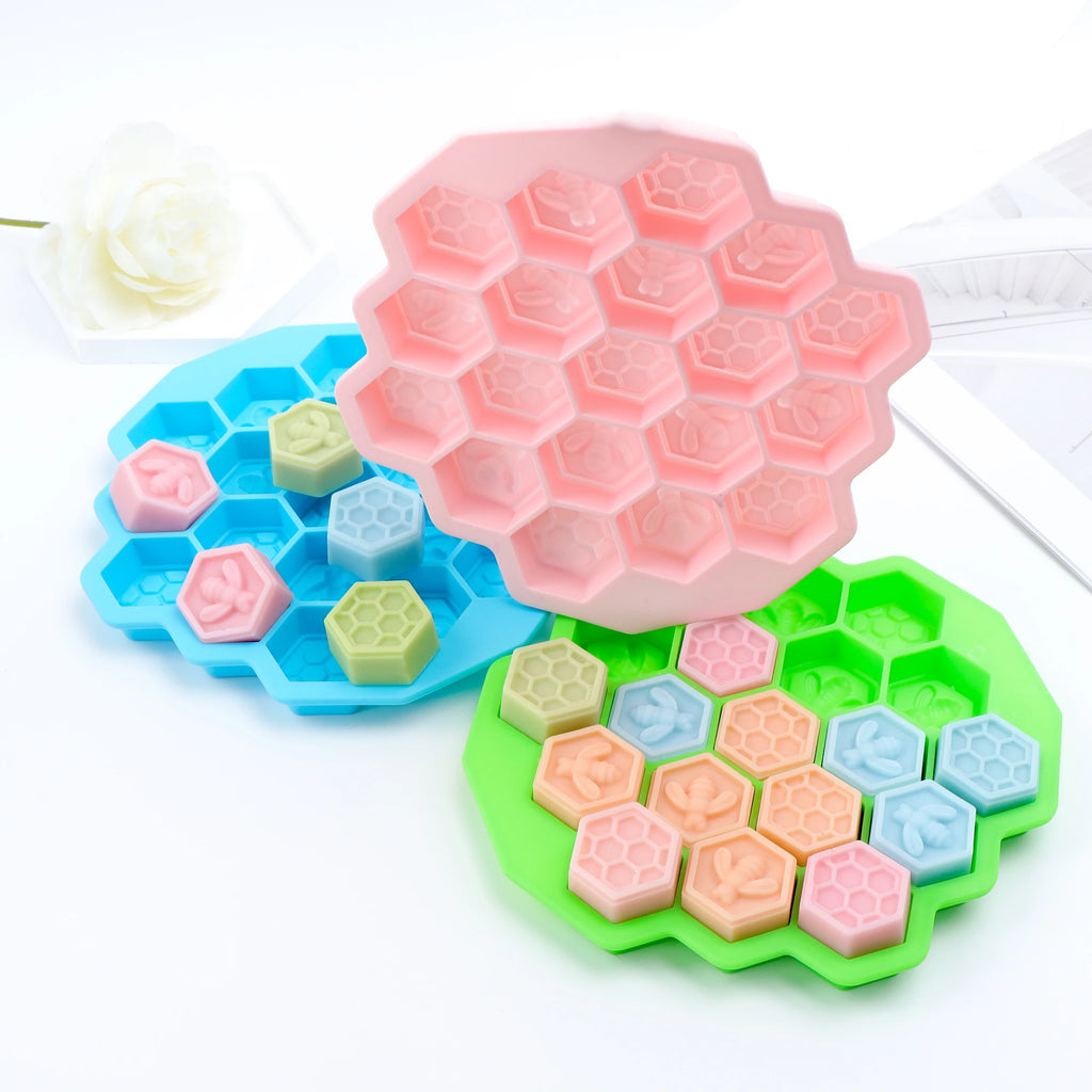 Pink, blue and green hexagonal molds displayed with scattered pastel bee and honeycomb castings