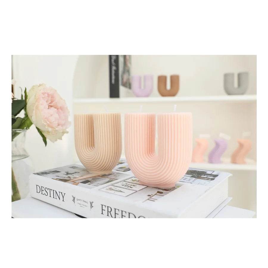 Two pink ceramic cups on a book with a blurred background of decorative items.