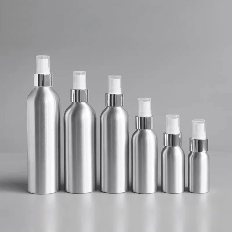 Silver aluminum spray bottles lined up by size against a gray background