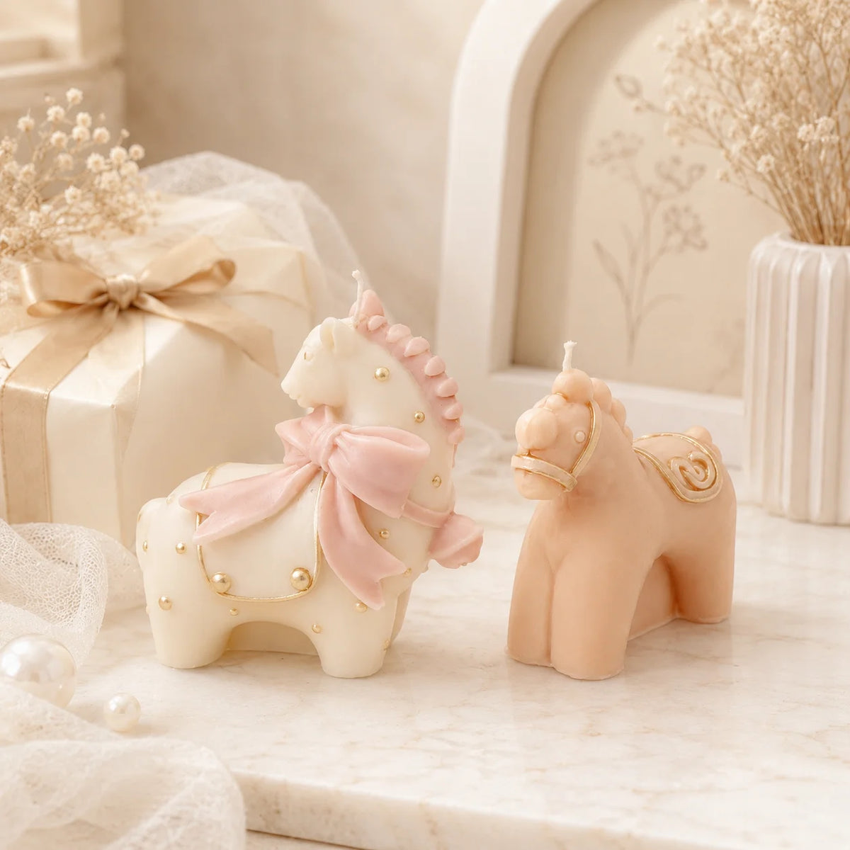 Ivory bow-adorned horse and peach standing horse example candles beside a ribboned gift box