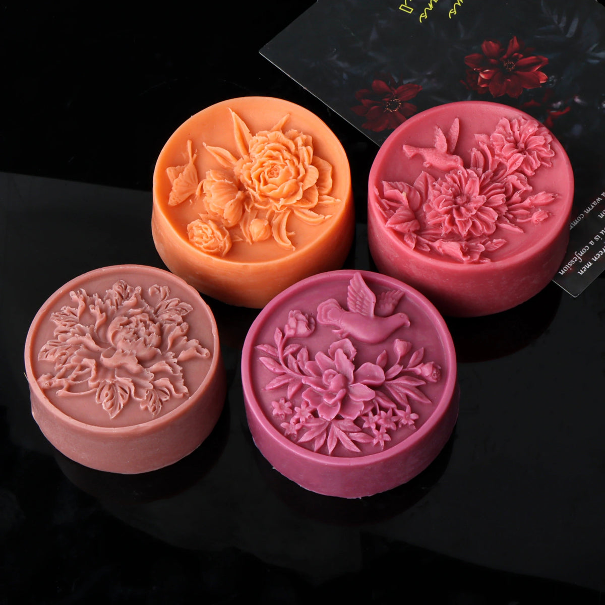 Four round floral relief casting examples in orange, pink and mauve, including bird and flower designs